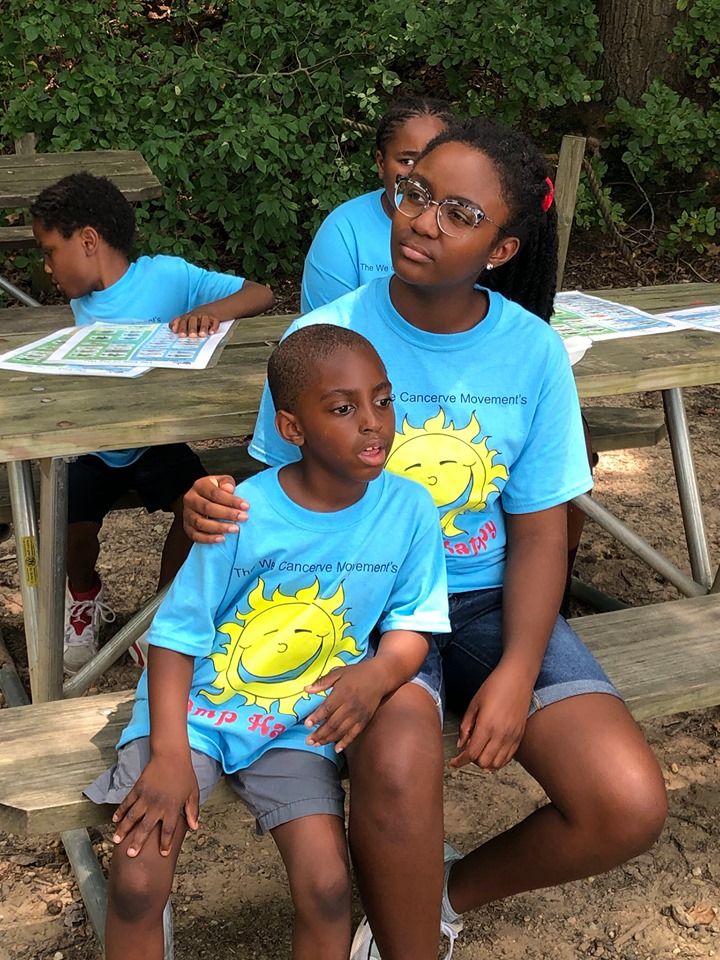 Grace Callwood (r), founder of  the WeCancerve movement and organizer of Camp Happy for children of Anna's House sits with a camper while visiting a Harford County nature center.
