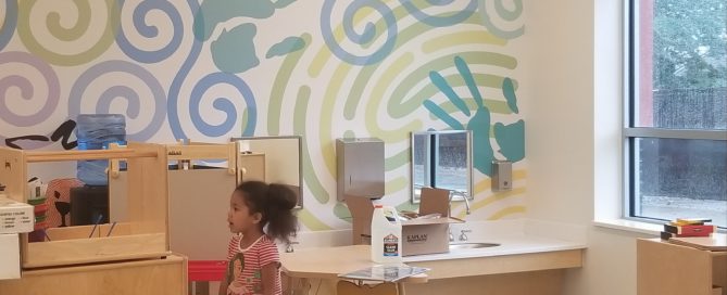 Little girl in classroom with colorfully painted walls